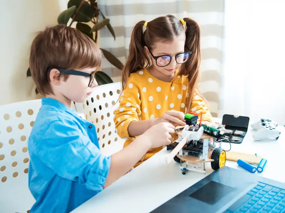 Dwoje dzieci wspólnie budujących robota edukacyjnego